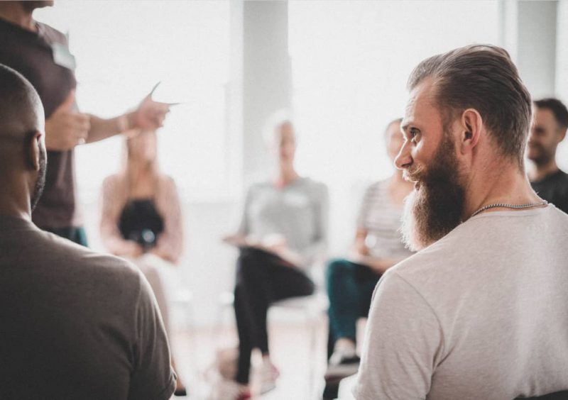 man turned to left speaking to another man beside him